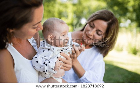 Baby being bottle-fed by two lesbian colombian women outdoors in a park setting