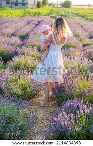 woman with daughter on lavender field happy dancing at sunrise on warm summer day. 