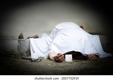 Woman Dead Body Laying Down Over Concrete Barrier With Hamer And Evidence Crime Scene Sign, Body Was Cover By White Cloth Waiting For Police Investiation For Cause Of Death.