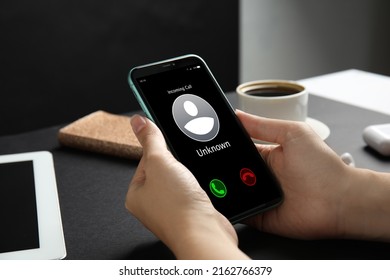 Woman deciding answer incoming call from unknown caller or not at table, closeup. Be careful - fraud - Shutterstock ID 2162766379