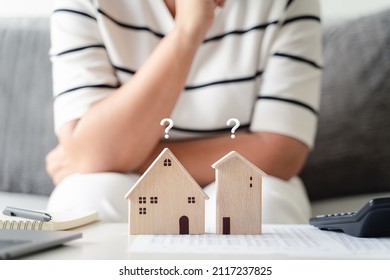 woman is deciding to choose house with Small Wooden House Model with Question Marks, Planning to buy property. Choose what's the best. home loan concepts.