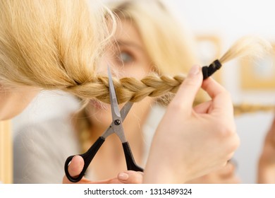 Woman Deciding To Cut Her Long Blonde Hair Tied In Braid. Hairstyle Change At Home.