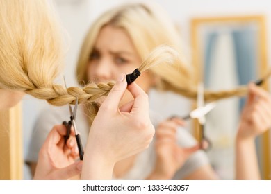 Woman Deciding To Cut Her Long Blonde Hair Tied In Braid. Hairstyle Change At Home.