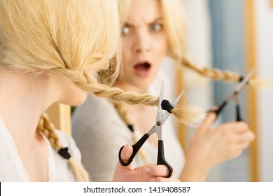 Woman Deciding To Cut Her Long Blonde Hair Tied In Braid. Hairstyle Change At Home.