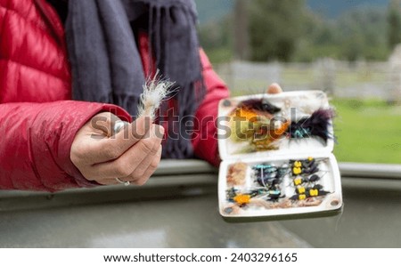 Woman deciding which fly to use for her fishing rod.