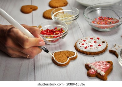 Woman decorate gingerbread cookies. Colorful glazed cookies. Christmas homemade cookies on wooden table. - Shutterstock ID 2088413536