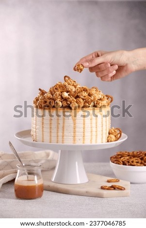 Woman decorating caramel drip cake at light table, closeup