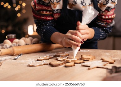 Woman decorating christmas gingerbread cookies with icing on wooden table. Decorating baked christmas cookies. Close-up - Powered by Shutterstock