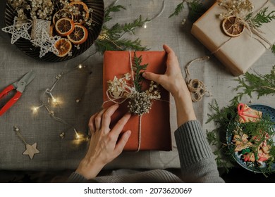 Woman decorating Christmas present with natural eco friendly materials. Zero waste Christmas gifts packaging. Table top view. - Powered by Shutterstock