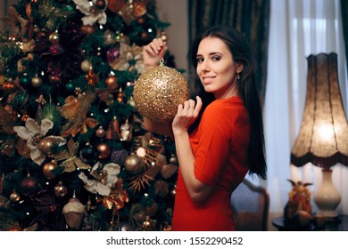 Woman Decorating Christmas Tree With Sparking Ornament. Party Host Preparing For Holidays Decorating The House
