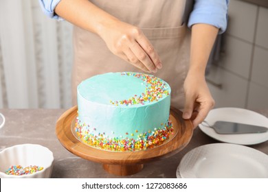 Woman Decorating Fresh Delicious Birthday Cake In Kitchen, Closeup