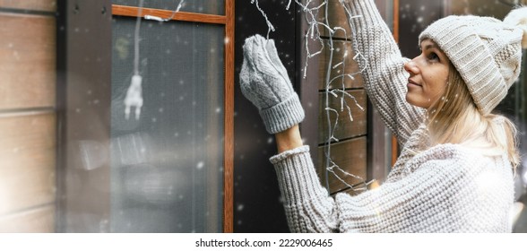 woman decorating house with christmas lights outdoors. banner with copy space - Powered by Shutterstock