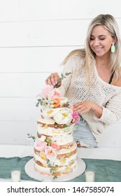 Woman Decorating Naked Wedding Cake With Flowers, Baker With Modern Style Tiered Cake, White Background