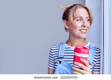 Woman Decorating Room At Home Taking A Break With Hot Drink In Reusable Cup