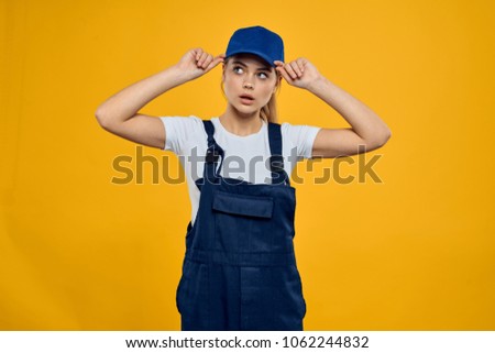   woman deliverer adjusts her cap on a yellow background                             