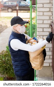 Woman Delivering Food In Paper Bag During Covid 19 Outbreak.Feme Volunteer Holding Groceries In The House Porch.Volunteer In The Protective Medical Mask And Gloves