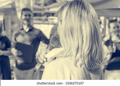 Woman delivering a speach in front of live audience outdoor.