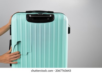 A woman demonstrates a broken suitcase on a white background. Damaged baggage during the flight.