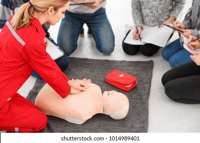 Woman Demonstrating CPR On Mannequin In First Aid Class