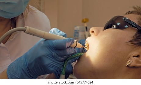 Woman at the dental hygienist and dentist clinic professional tooth whitening and ultrasound cleaning. Odontic and mouth health and hygiene is important part of human life that dentistry help with.