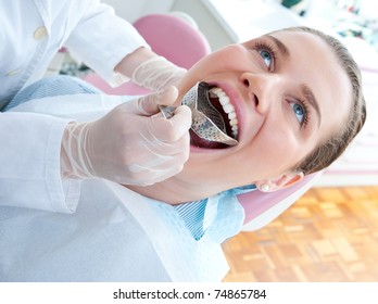 Woman In Dentist Chair With Dental Impression Tray In Her Mouth
