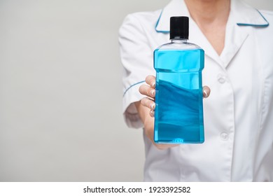 Woman Dentist Doctor Holding Bottle Of Mouthwash Standing Over Grey Background