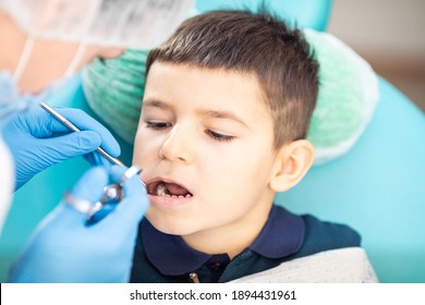 Woman dentist examines child's teeth using metal instruments - Powered by Shutterstock