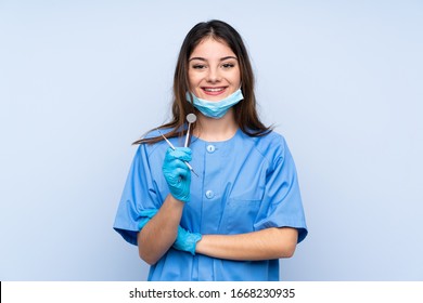 Woman dentist holding tools over isolated blue background laughing - Powered by Shutterstock