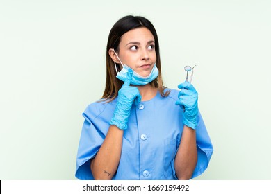 Woman dentist holding tools over isolated green background thinking an idea