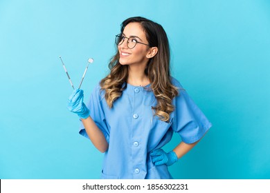 Woman dentist holding tools over isolated on blue background thinking an idea while looking up