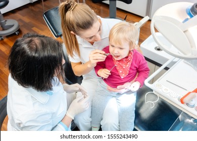 Woman Dentist Looking After Baby Teeth Of A Little Girl In Her Surgery