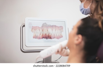 Woman dentist scanning patient's teeth with 3d dental scanner in modern clinic, 3d jaw scanner screen.