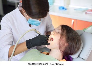 Woman dentist treating teeth to a patient sitting in dental chair using professional equipment. Dentistry, healthy teeth, sedation, medicine and healthcare concept - Shutterstock ID 1627126768