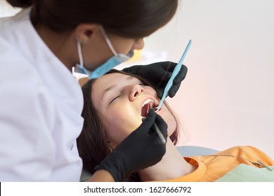 Woman dentist treating teeth to a patient sitting in dental chair using professional equipment. Dentistry, healthy teeth, sedation, medicine and healthcare concept - Shutterstock ID 1627666792