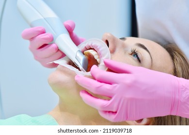 Woman dentist using dental intraoral scanner while examining patient teeth in dental clinic. Intraoral scanning with scanning machine concept. Close up