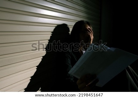 Woman depressed from sad stress pain despair problem, person sit on closed shop on corridor alone with emotion lonely desperate upset head down. Head in hand no way out concept, copy space