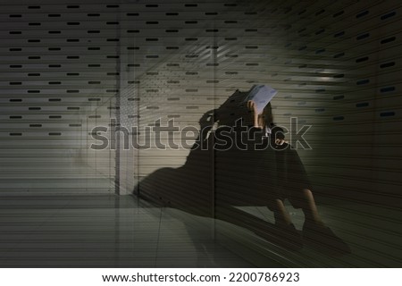 Woman depressed from sad stress pain despair problem, person sit on closed shop on corridor alone with emotion lonely desperate upset head down. Black Dark Underexposure concept, copy space