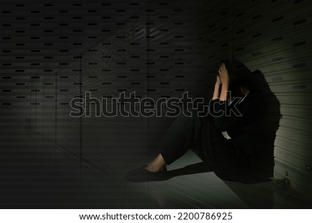 Woman depressed from sad stress pain despair problem, person sit on closed shop on corridor alone with emotion lonely desperate upset head down. Black Dark Underexposure concept, copy space