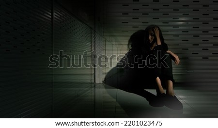 Woman depressed from sad stress pain despair problem, person sit on closed shop on corridor alone with emotion lonely desperate upset head down. Black Dark Underexposure concept, copy space