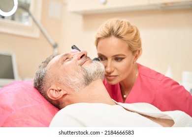 Woman dermatologist examines the neck of man with dermatoscope