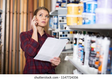 Woman Designer Is Choosing Paint With List For Redecorate House And Talking By Phone In The Store