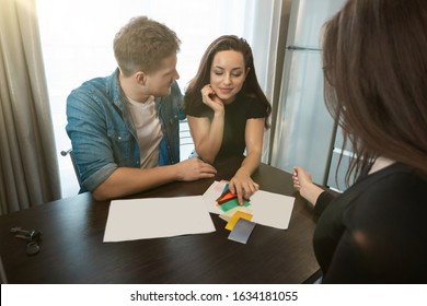 woman designer consulting young couple husband and wife on wall colours using color palette sitting in new apartment wife picking up right shade. - Powered by Shutterstock