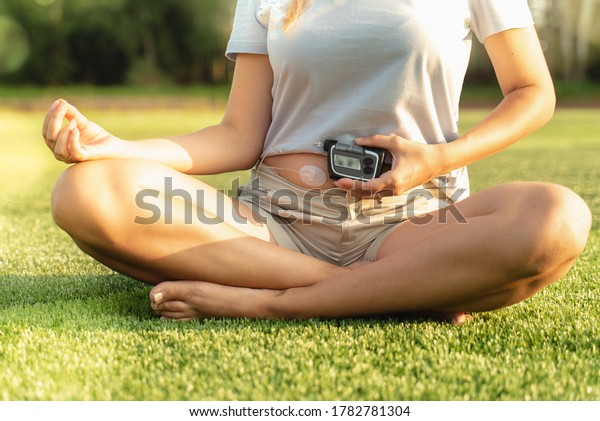 \
Woman with diabetes is doing\
yoga. The girl holds an insulin pump in her hands. A woman is\
sitting on the grass in the park. Healthy lifestyle with\
diabetes