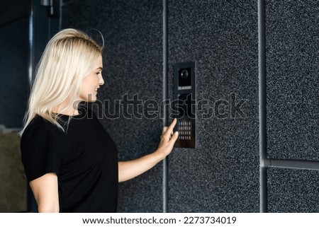 woman dialing an intercom to enter a building