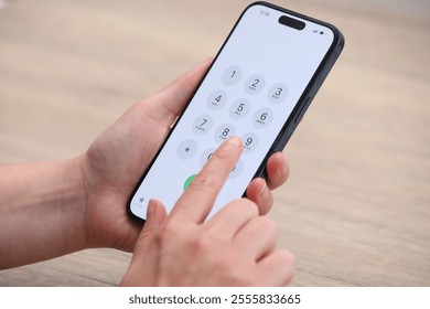 Woman dialing number on smartphone at wooden table, closeup - Powered by Shutterstock - Get 15% off with code: PIKWIZARD15
