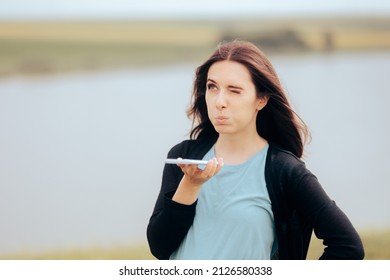 

Woman Dictating A Message On A Mobile Phone. Girl Listening To Voicemail Standing Outdoors In Nature
