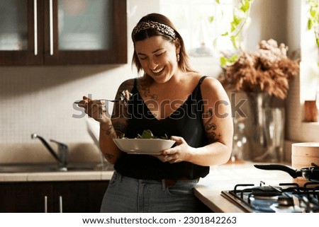 Woman, diet and person eating salad in her home kitchen and is happy for a meal with nutrition or healthy lunch. Smile, food and young female vegan in her apartment or house and eat vegetables
