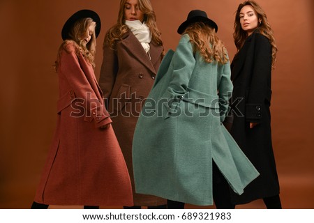 Woman in different colorful long coats, black. brown, dark red, green, with scarf and black hat, with wavy hair on brown background in motion