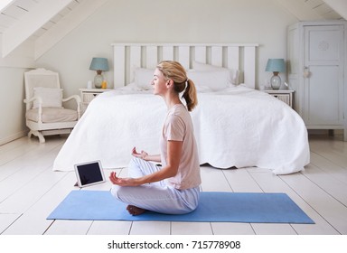 Woman With Digital Tablet Using Meditation App In Bedroom