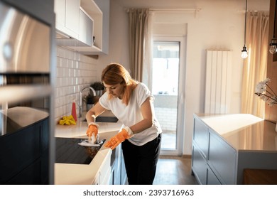 Woman diligently cleaning her kitchen countertop - Powered by Shutterstock